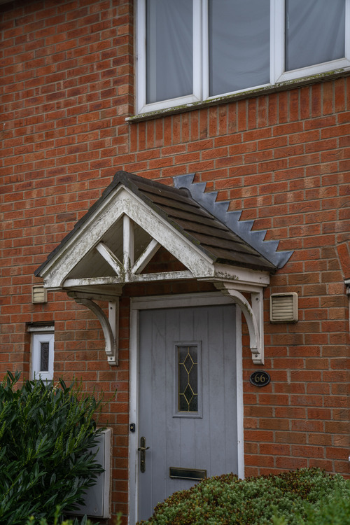 Painted wood door canopy with heavy green algae growth on the gable corbels and underside before cleaning