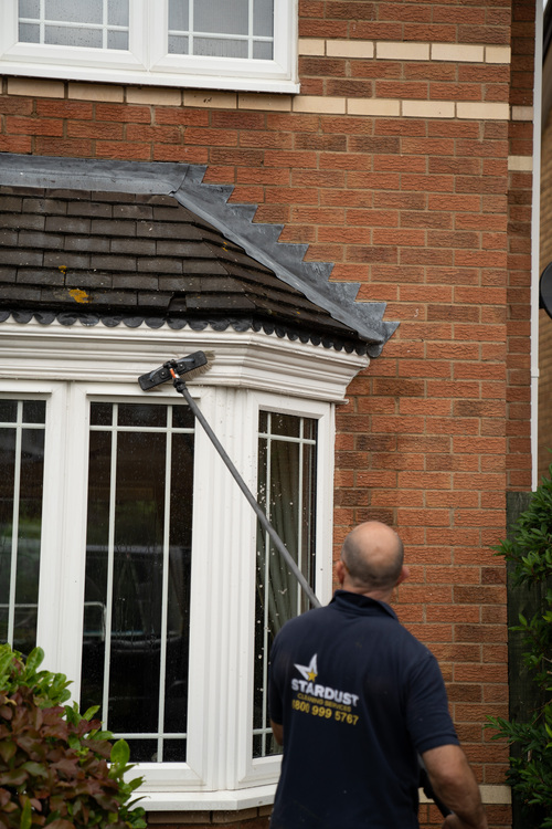 Soft brush head on water-fed pole gently cleaning painted moulding above a bay window using pure water