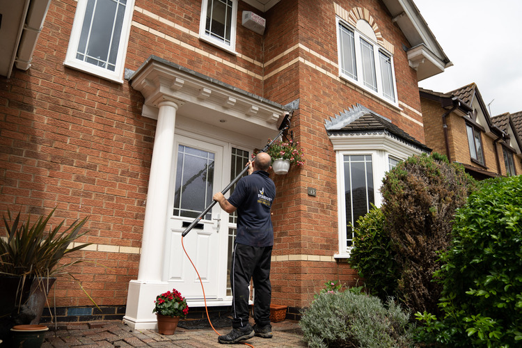 Stephen Fudge using a water-fed pole to clean the fascia and portico of a detached property in Nottingham working from ground level in branded Stardust uniform